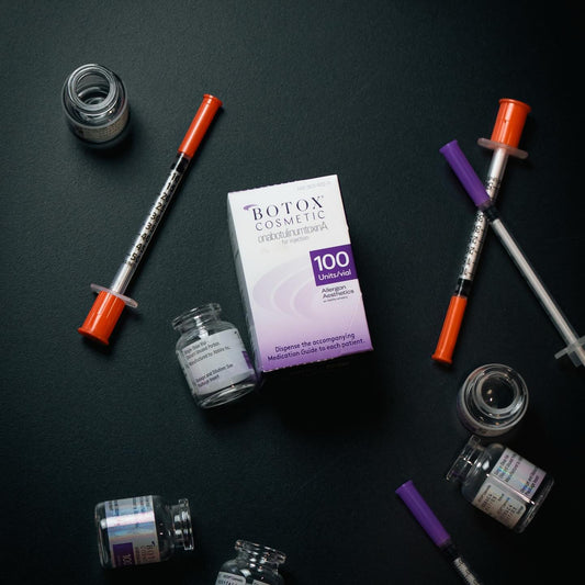 Botox cosmetic vials and syringes arranged on a dark surface for injectable treatment preparation