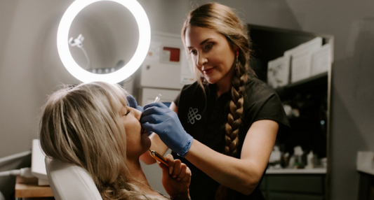 Clinician administering a facial injectable treatment to a patient in a medical spa setting with ring light illumination