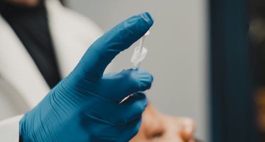 Gloved hand holding a syringe near a patient’s face during preparation for an injectable treatment