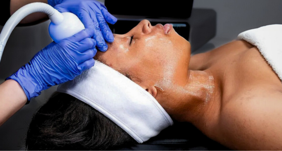 A person receiving a cryo facial treatment, where the skin is being exposed to cold therapy using a machine.